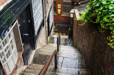 在雨季的春天, 一座旧建筑和一堵砖墙之间的狭窄楼梯。纽卡斯尔在泰恩, 英国, 英国