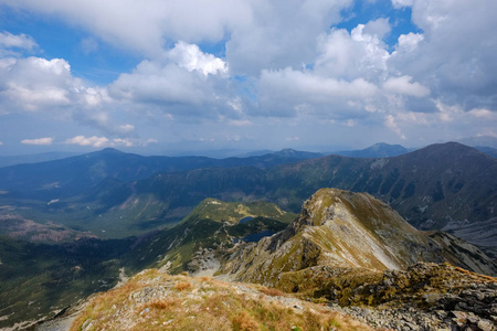 从斯洛伐克的 Banikov 山顶的山脉全景塔特拉山脉与岩石景观和远足者的阴影在明亮的天与风暴云接近在阴天