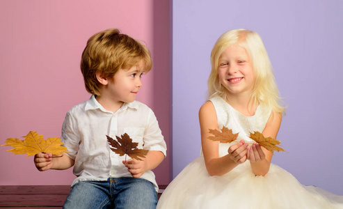 孩子们玩树叶坠落的乐趣。可爱的孩子拿着金箔在颜色背景