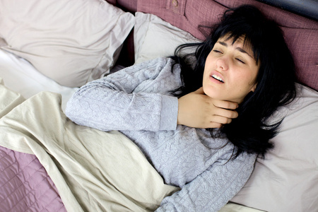 发烧生病女人在床上生病发烧和喉咙问题照片