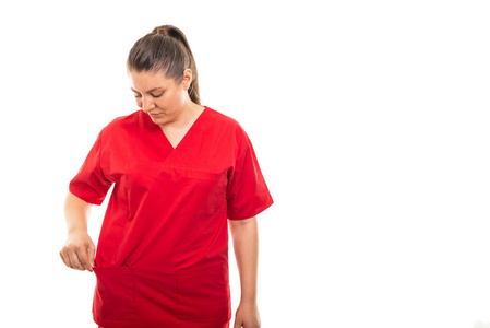 年轻医护护士的肖像穿着红色擦洗看着口袋里的白色背景与 copyspace 广告区