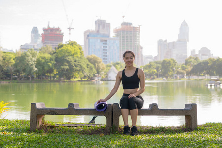 美丽的亚洲妇女坐在公园准备锻炼