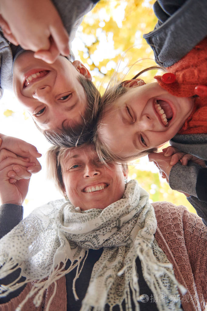 母亲和孩子们在秋城公园他们是父母摆姿势微笑玩耍和乐趣明亮的黄色树