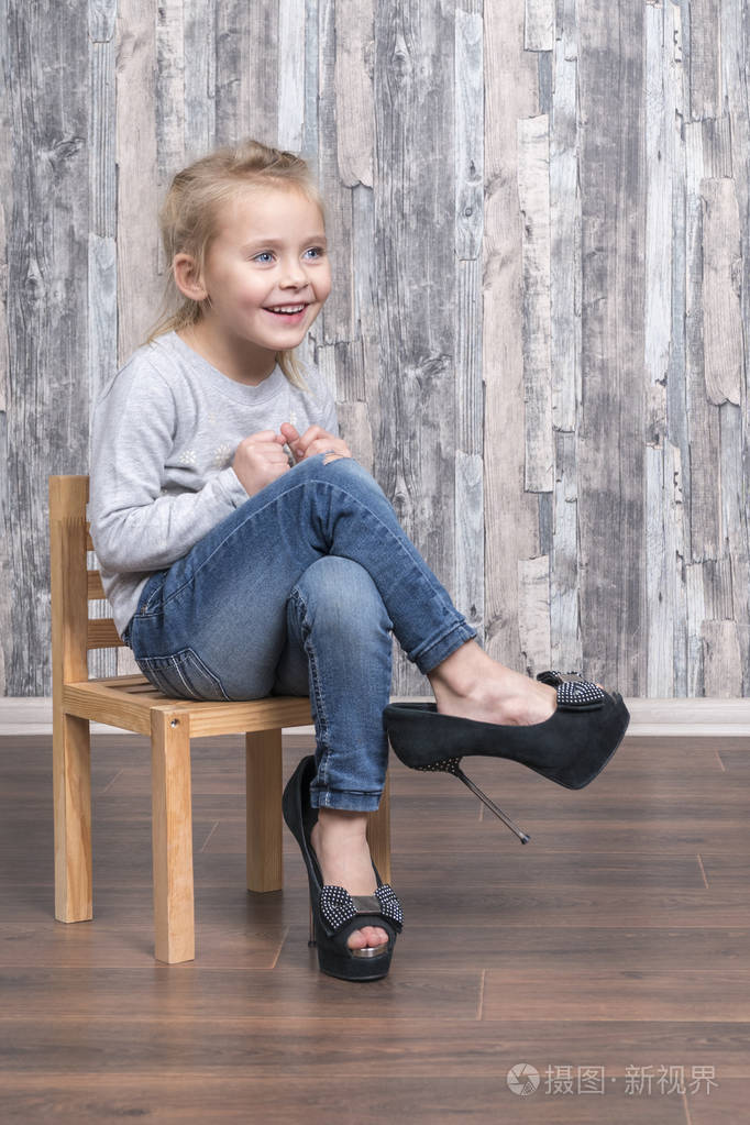 快乐的小女孩坐在木椅上穿着母鞋