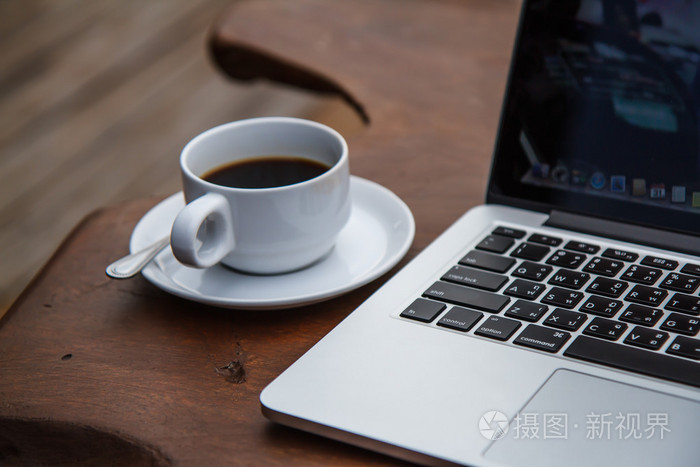 在与一台电脑桌上的白杯黑咖啡