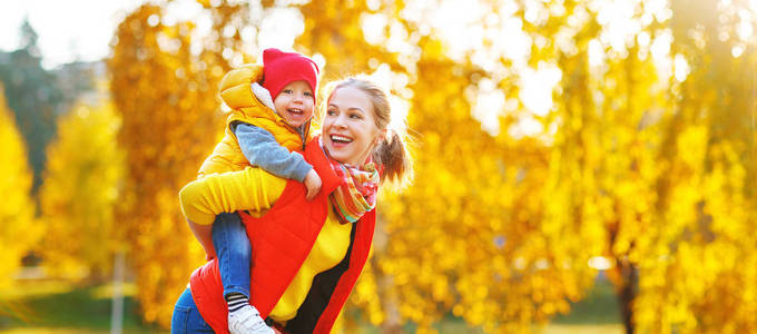 快乐家庭母亲和襁褓中的儿子玩又笑秋步行