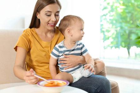 妇女喂养她的孩子在高脚室内。健康婴儿食品