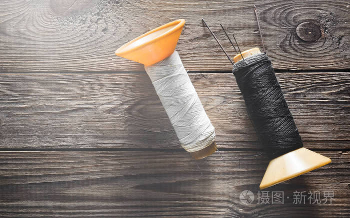 白色和黑色线圈的螺纹与针在质朴的木制背景.顶部视图