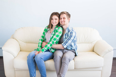 一对年轻的情侣在沙发上休息的肖像在家里和拥抱