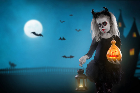 吸血鬼孩子万圣节化妆的小女孩.魔鬼的形象与牛角和南瓜照片