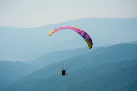在阳光明媚的夏日, 滑翔伞飞过山谷。夏季喀尔巴阡山的滑翔伞