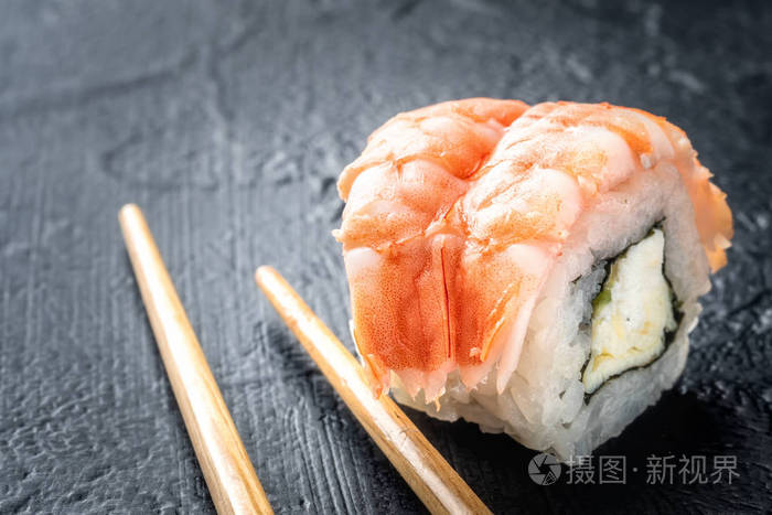 寿司卷鲜虾米饭和费城乳酪亚洲食物在黑暗的背景下用筷子