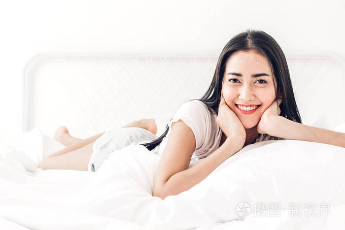 美丽的女人在床上放松在她的房间在家里
