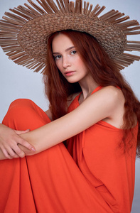 时髦的女人, 红色的头发摆在礼服和草帽, 孤立的灰色
