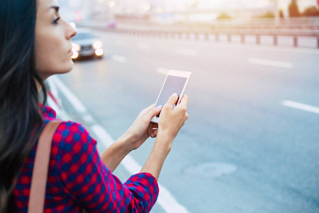在城市道路侧使用智能手机的年轻休闲妇女