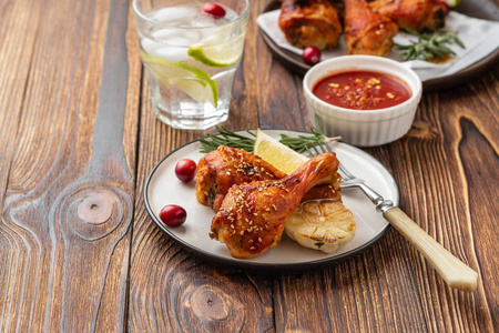 美味可口的烤鸡腿, 配以香料迷迭香和红莓, 放在木制背景桌子上。圣诞菜。复制空间