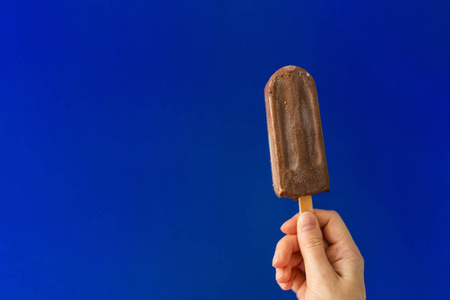 女孩的手与巧克力冰淇淋在深蓝色背景