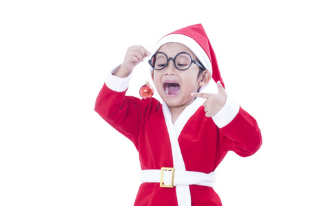 快乐的小男孩穿圣诞老人制服及手持红色圣诞球