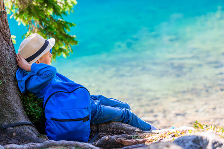 男孩疲倦的旅行者用背包休息在湖在 Tatra 山