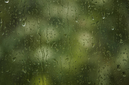 雨落在窗口与绿色树在背景