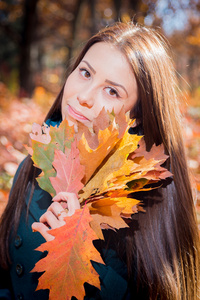 束树叶在秋天的公园里的女孩