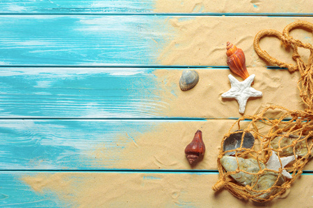 海绳索与海贝壳在海沙子在蓝色木背景。顶视图
