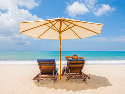 放松与阳伞在白色沙滩上的沙发椅子