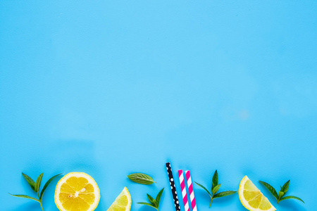 创意布局的柠檬片, 薄荷叶和彩色稻草在柔和的蓝色背景。鸡尾酒和柠檬水的夏季配料。平躺, 顶部视图