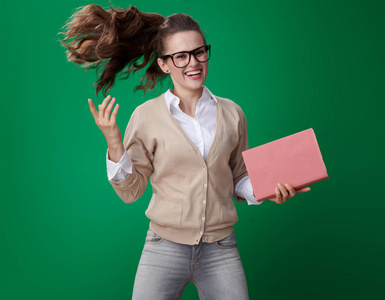 快乐的现代学生妇女与书跳跃在绿色背景