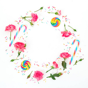 圆框架的玫瑰花与花瓣和明亮的糖糖果在白色的背景。平躺, 顶部视图