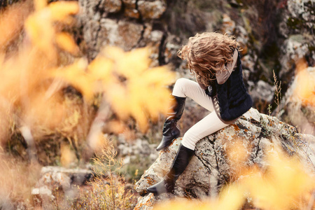 女人坐在岩石上, 覆盖着浓密的头发, 悲伤