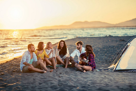 夏日日落海滩上放松的朋友们照片