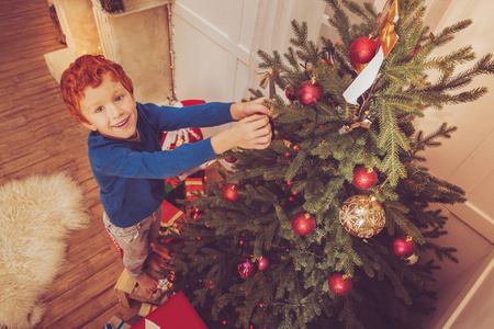 装饰圣诞树的可爱的红头发男孩的顶部视图