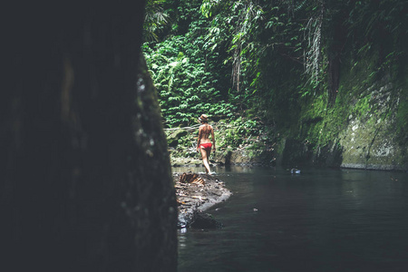 后视图的年轻妇女游客与草帽和红色泳装在深丛林。真正的冒险概念。巴厘岛