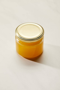 白色表面玻璃罐中甜有机蜂蜜的特写图