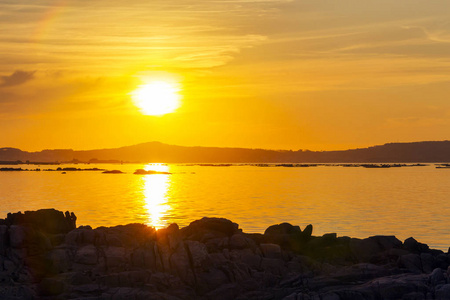 Arousa 河口在金色日落与沿海岩石在前景上