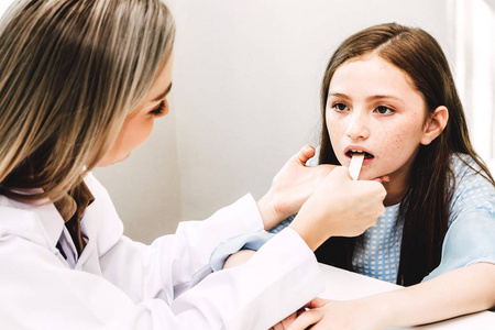 医生在口腔检查和检查与小女孩的喉咙在医院. 保健和医药