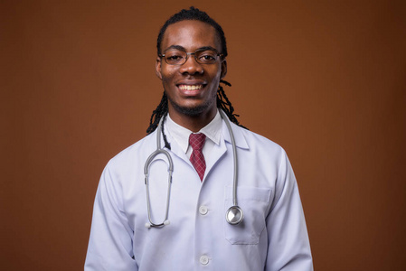年轻英俊的非洲人医生反对棕色背景