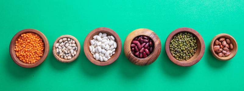 健康饮食观念。绿色背景, 隔离, 顶部, 横幅的木碗中的豆类品种