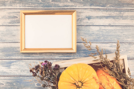 秋天橙色南瓜和干燥的花与草感恩节背景蓝色色调木桌与金色框架模拟和复制空间质朴风格, 模板文本