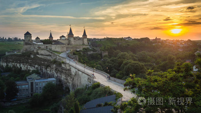 童话般的看法在 KamianetsPodilskyi 城堡, 乌克兰。日出以上 KamianetsPodilskyi 城市