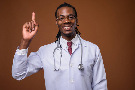 年轻英俊的非洲人医生反对棕色背景