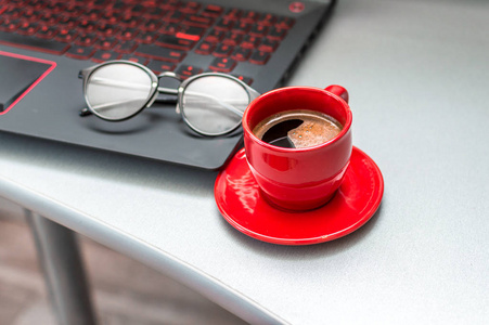 一杯咖啡, 一台笔记本电脑和眼镜在你的桌面上。经营理念