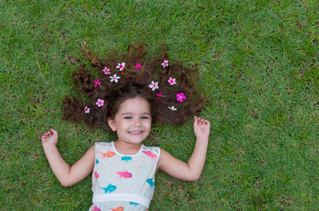 美丽和快乐的女孩在公园玩, 与美妙的草坪和花卉