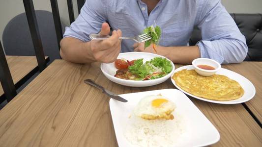 泰国菜米饭, 煎蛋卷, 蔬菜猪肉。一个人在餐馆里吃泰国菜