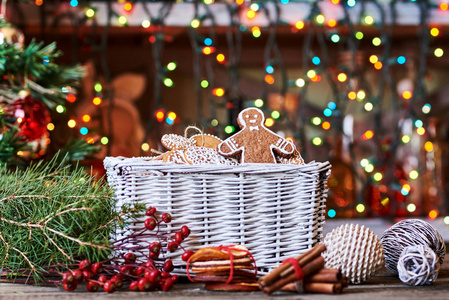 绿色云杉树枝, 锥体, 柳条篮子与姜饼, 球在闪耀的圣诞节背景
