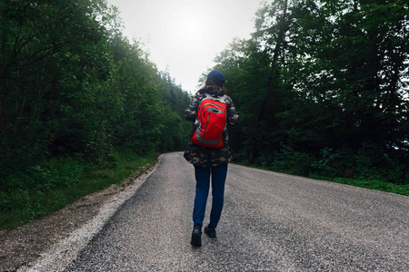 女人背着背包走在路上。旅游生活方式概念