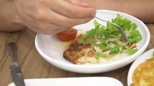 泰国菜米饭, 煎蛋卷, 蔬菜猪肉。一个人在餐馆里吃泰国菜