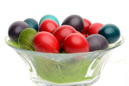 特写上多彩的手染复活节蛋放在一个玻璃碗装饰着草
