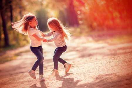 两个小女孩跳舞和乐趣一起在户外